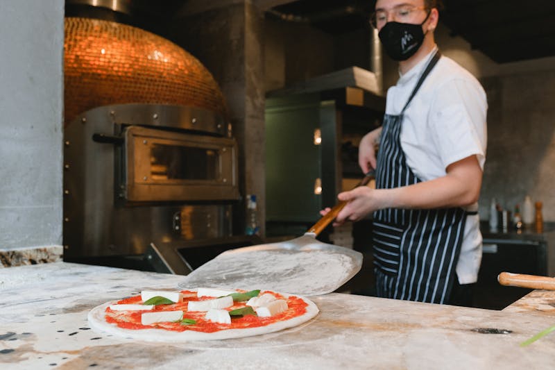 Anthony's coal fired pizza being prepared in a traditional coal-fired oven